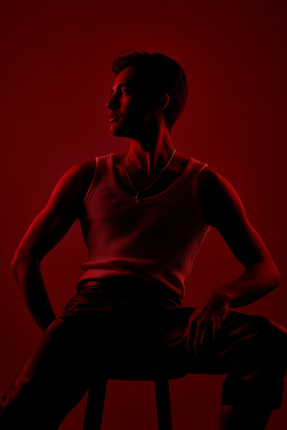 A male model standing with a red back light by Emily Teague