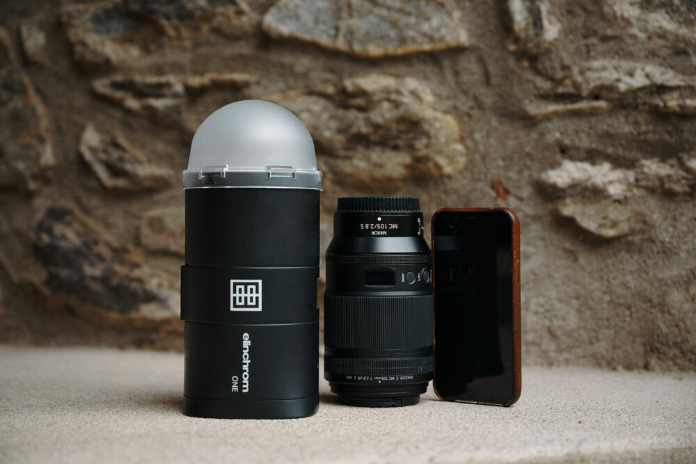 Elinchrom ONE's size compared to a camera lens and a smartphone