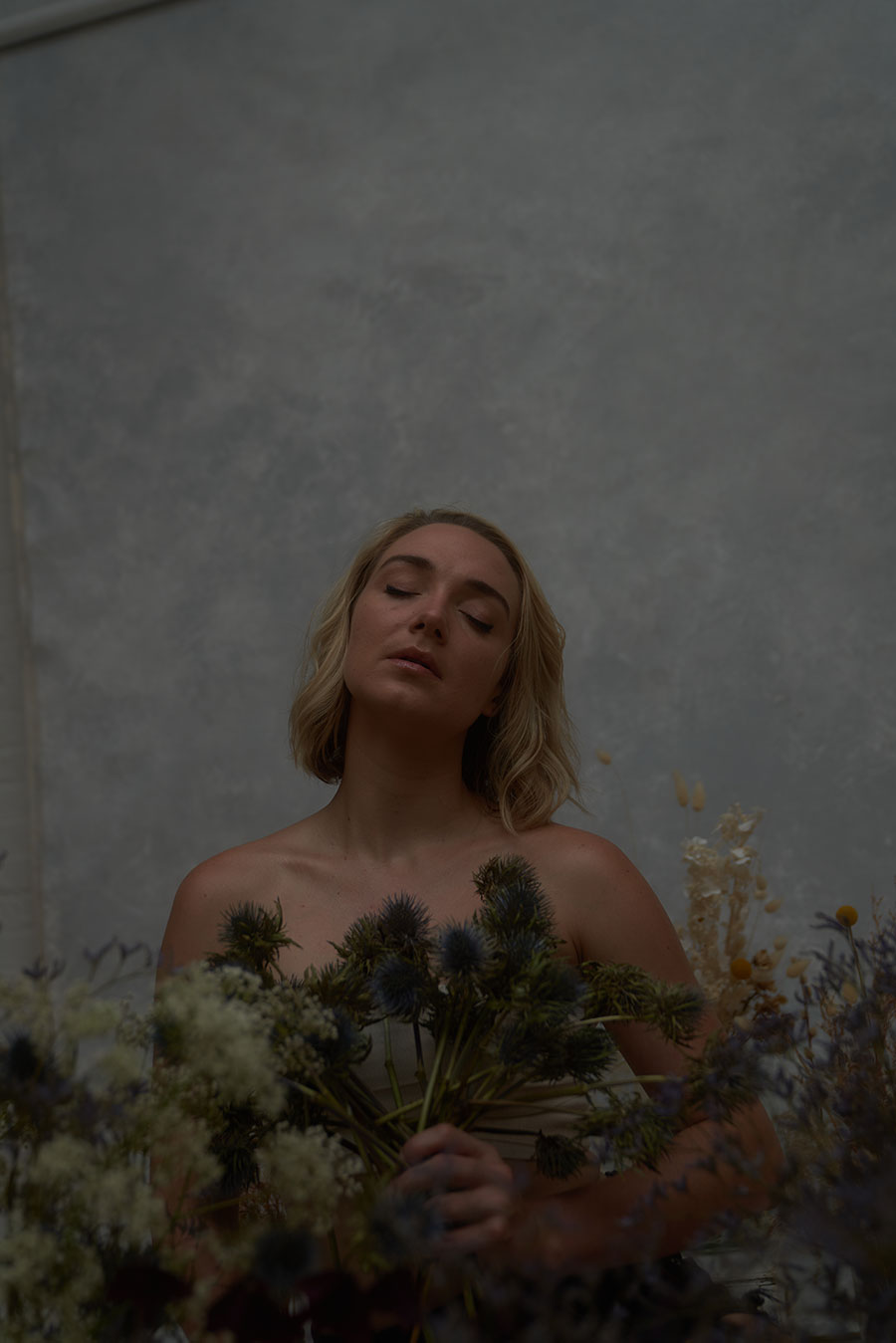 female model with dried flowers and grey packground