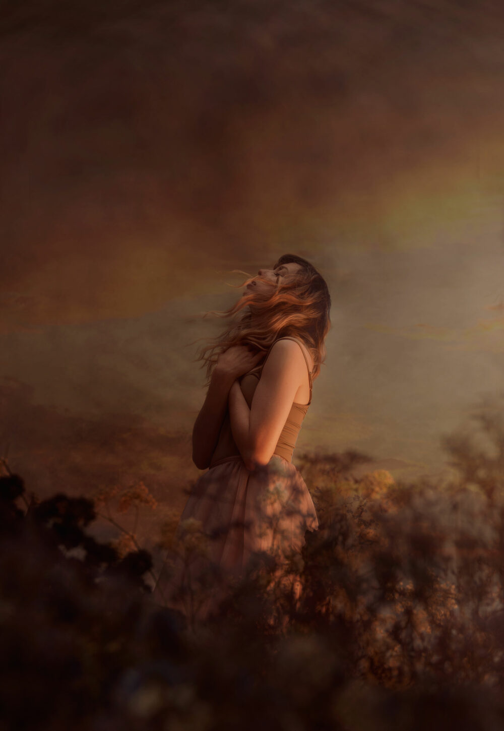 Female model standing in between dried flowers, with a red polluted sky